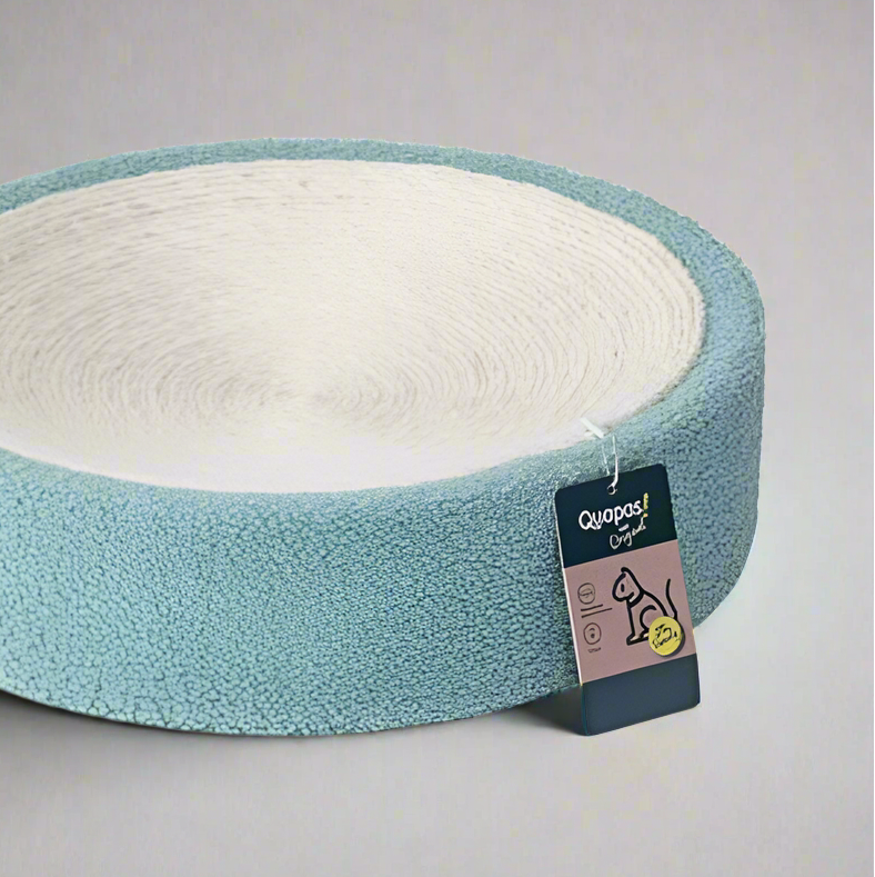 A round, mint green cat scratcher made of sisal with a white label attached displaying the brand name 'Quapas!'