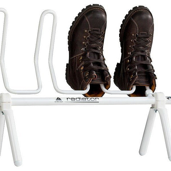 A white radiator-style shoe dryer with brown shoes placed on it, designed by Alpenheat to dry footwear.